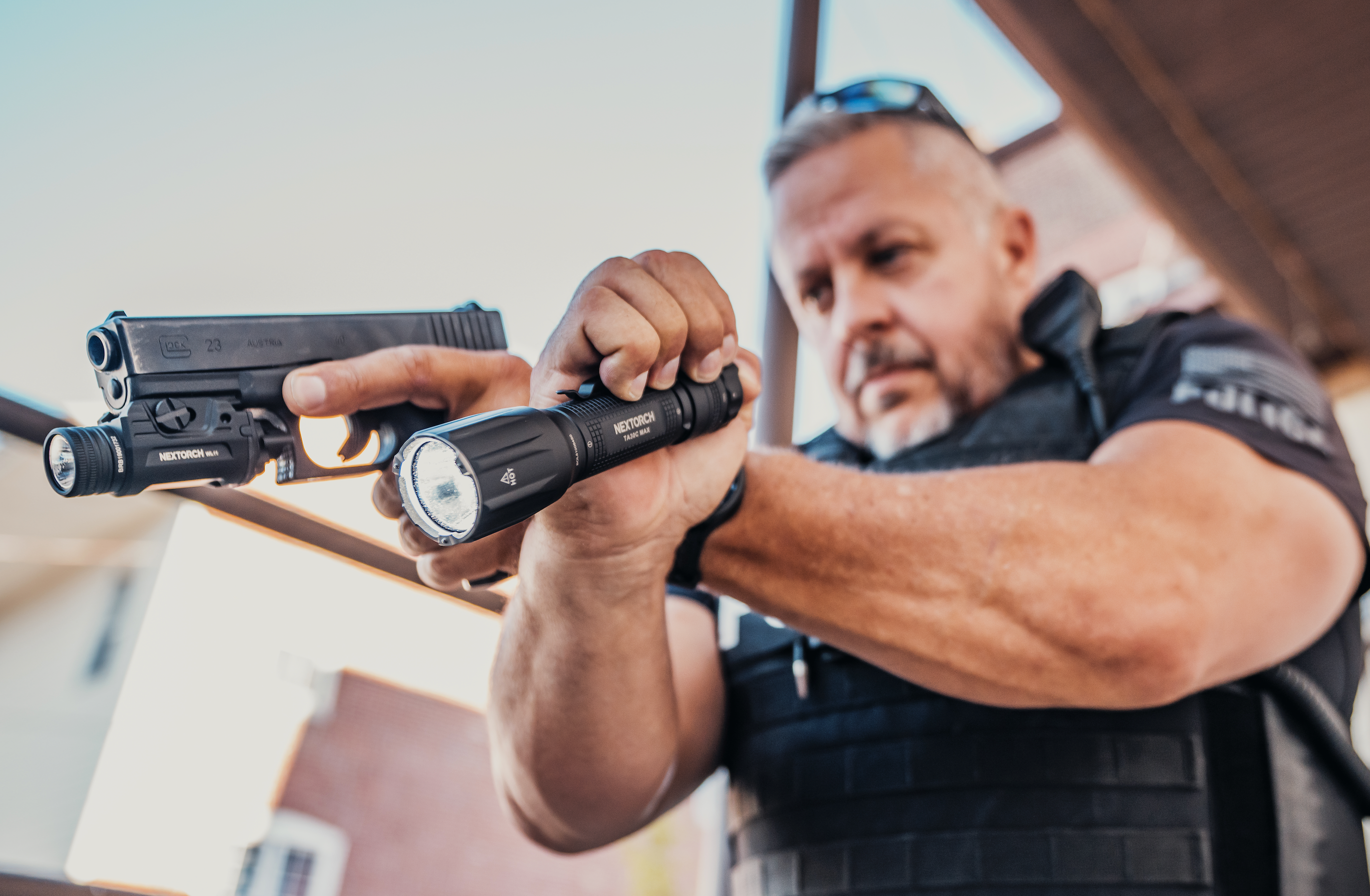 White male officer holding a tactical flashlight and mounted weapon light. 